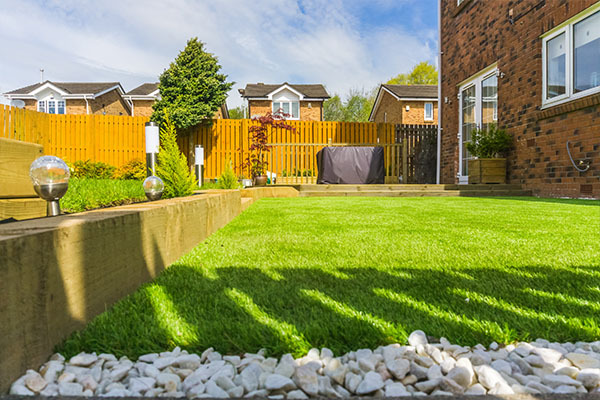 Simple landscaped garden with stones, lawn and raised decking